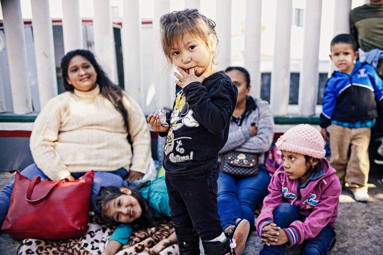 A young child licks her finger as other family members look on.